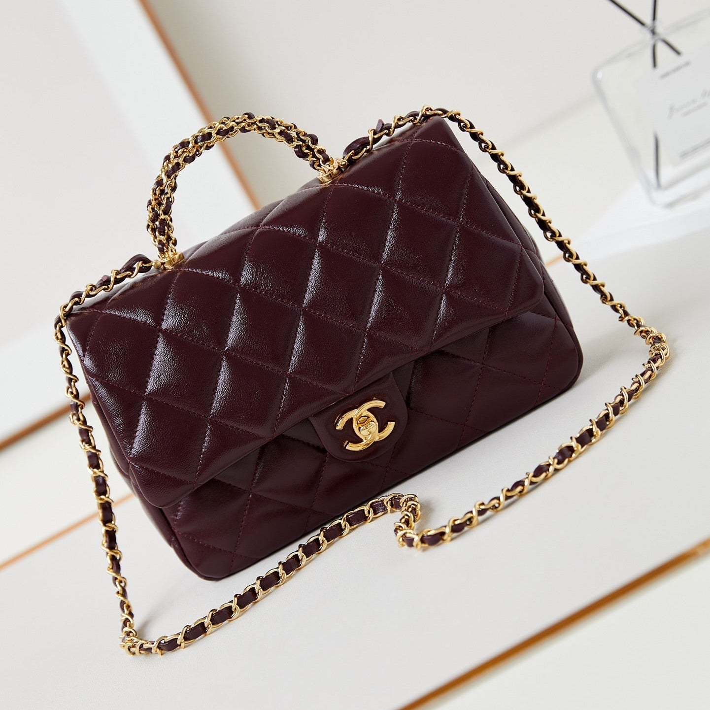 SAC À RABAT AVEC POIGNÉE SUPÉRIEURE 25 EN PEAU D'AGNEAU HUILÉE ET CIRÉE ROUGE BOURGOGNE, ACCASTILLAGE DORÉ