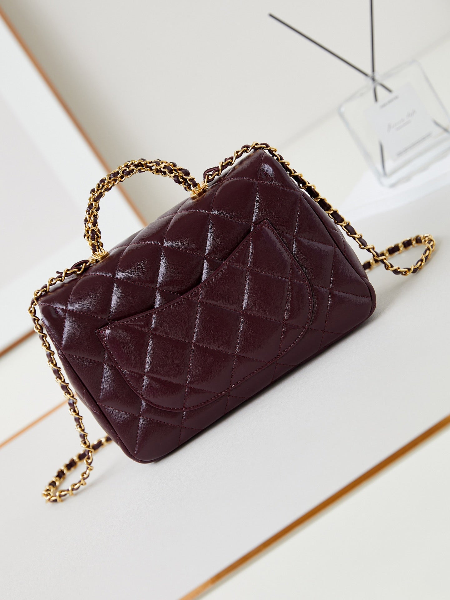 SAC À RABAT AVEC POIGNÉE SUPÉRIEURE 25 EN PEAU D'AGNEAU HUILÉE ET CIRÉE ROUGE BOURGOGNE, ACCASTILLAGE DORÉ